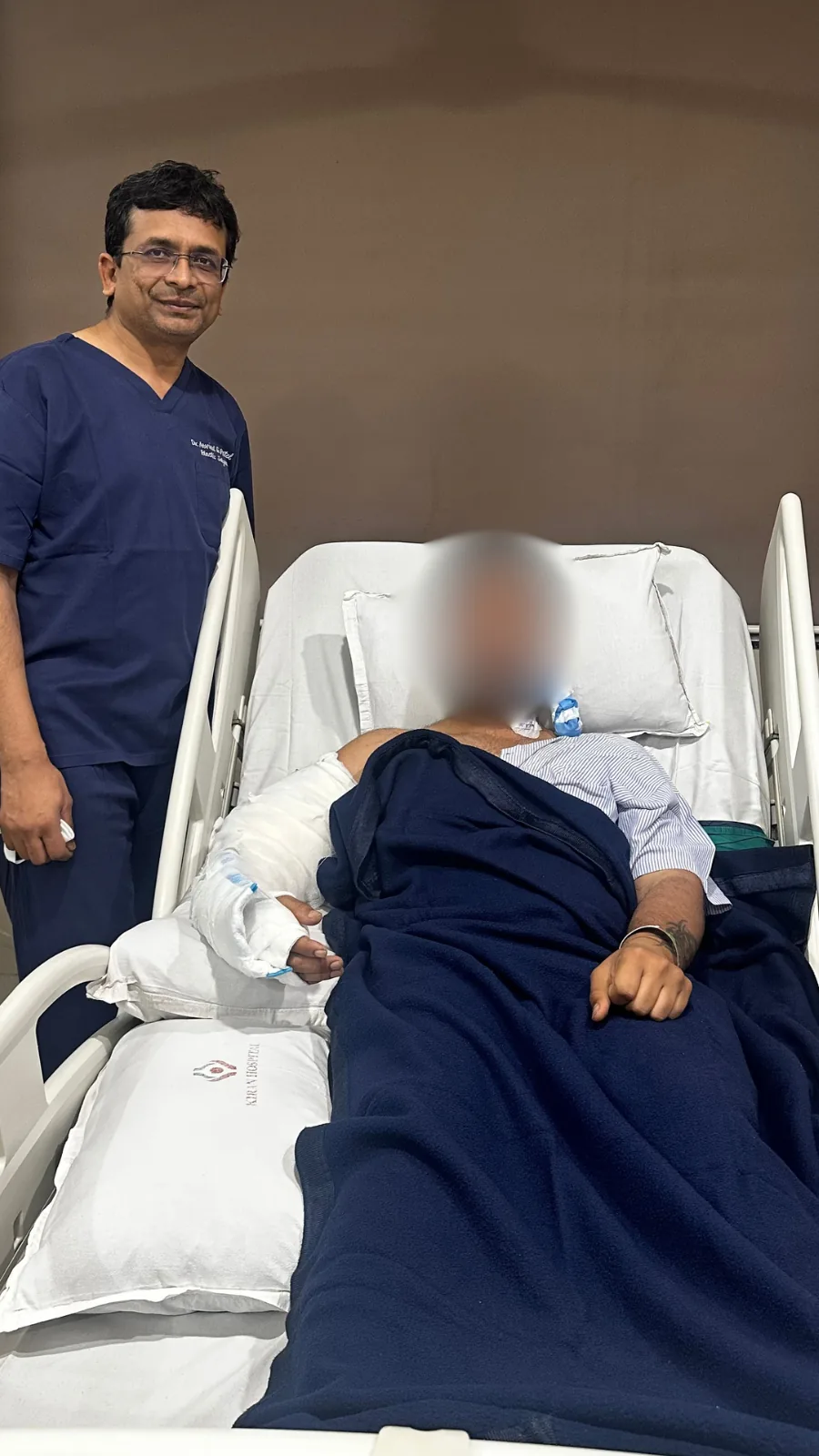 A hand transplant recipient recovering on the ward at Kiran Hospital, Surat, with Dr. Arvind Patel